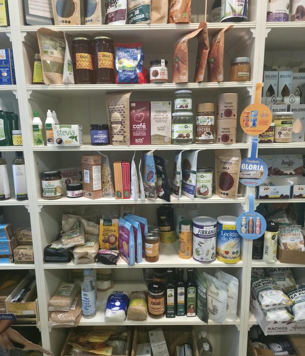 Estanterías blancas de la tienda llenas de tés, cafés, mieles y productos naturales.