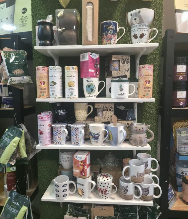Baldas blancas sobre la pared de césped con tazas, latas de té e infusiones.